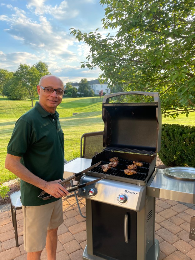 Tongs in hand, barbecuing chicken.